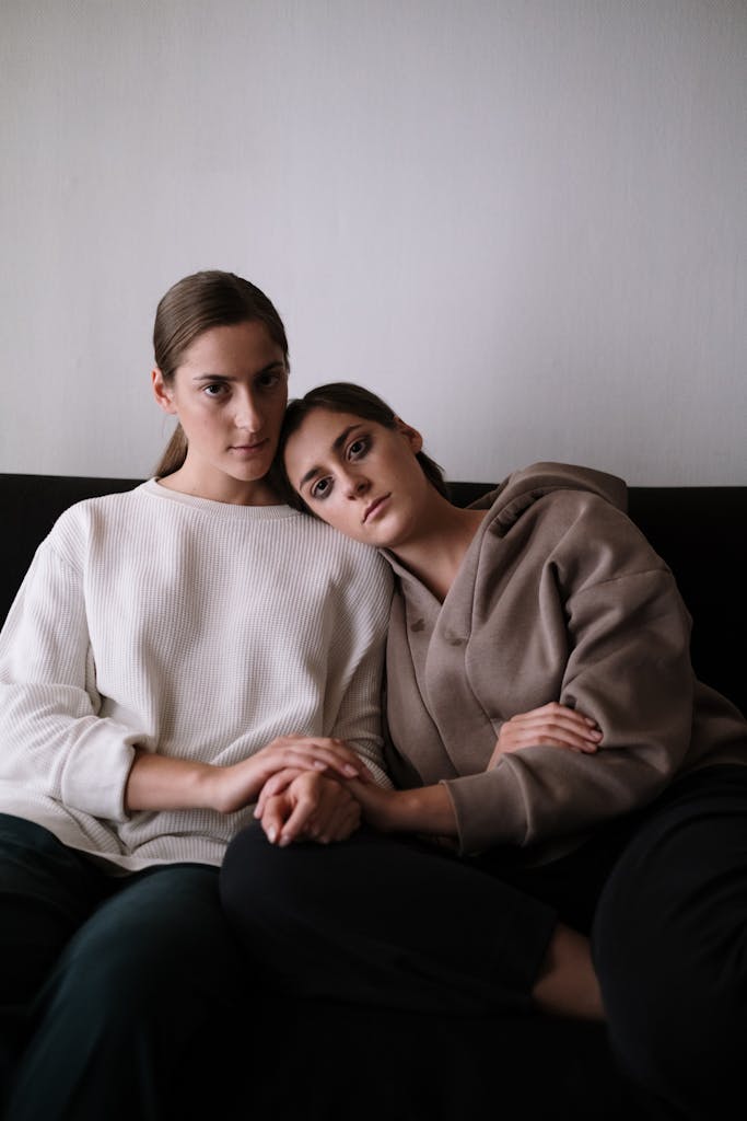 Two women share a tender and intimate moment on a sofa, symbolizing support and togetherness.