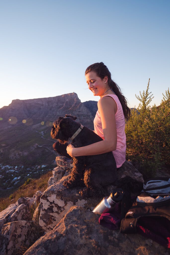 Woman enjoying sunset hike with her dog on a rocky hill overlooking Cape Town.