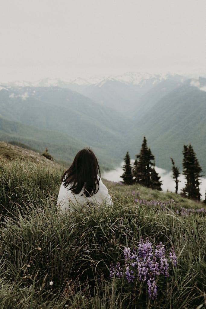 Woman enjoys a serene mountain view in Washington, surrounded by lush greenery and wildflowers.