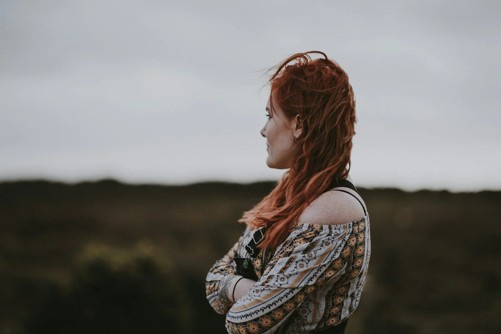 woman in white, orange, and black floral off-shoulder shirt crossing arms