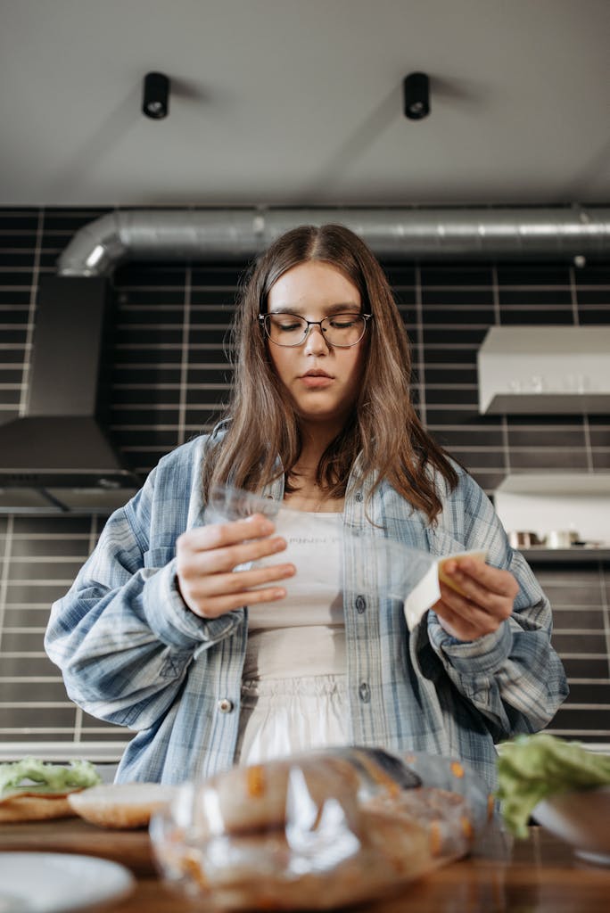 Young woman reading a recipe while preparing a meal in a contemporary kitchen.