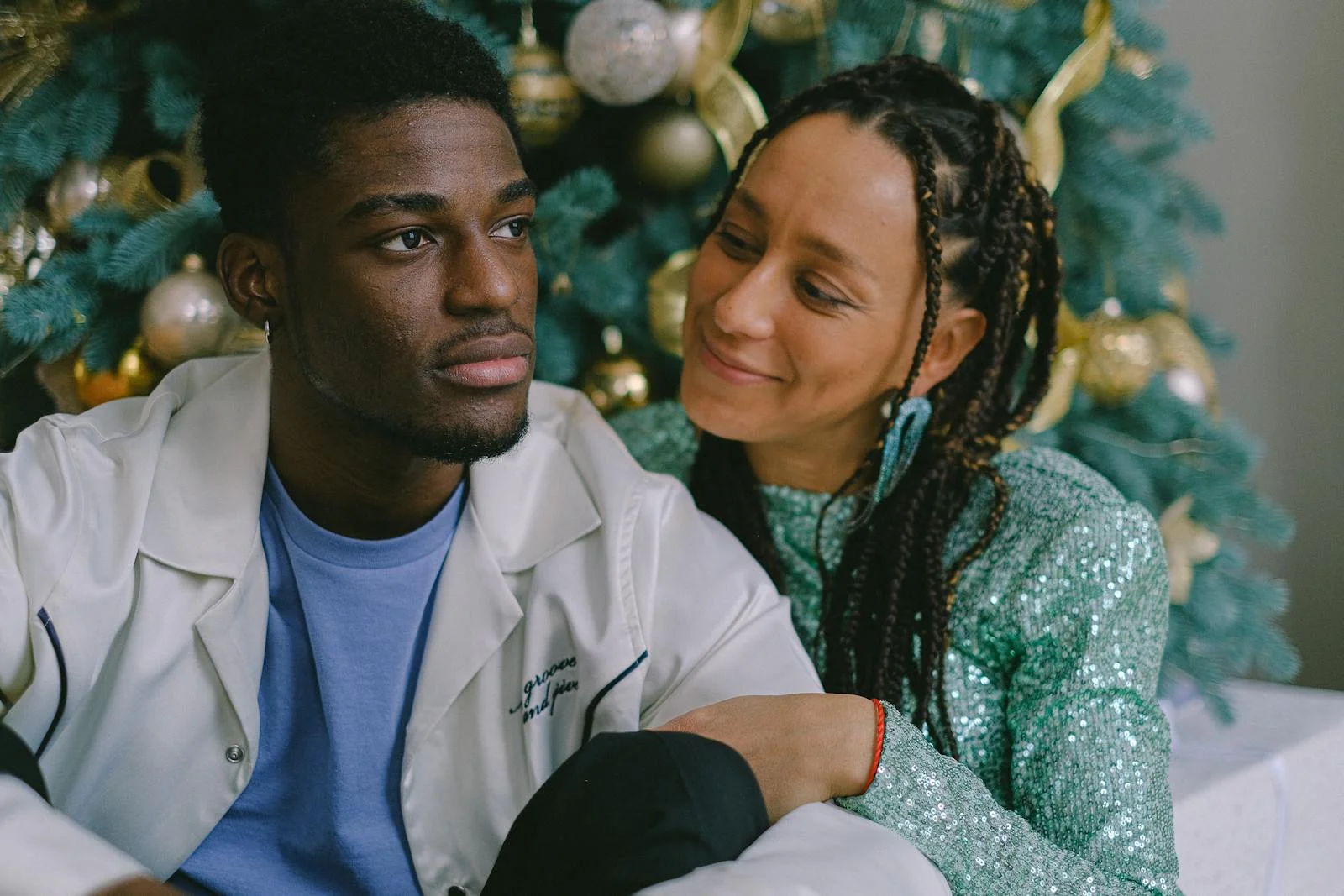A loving couple enjoys holiday time by the decorated Christmas tree indoors.