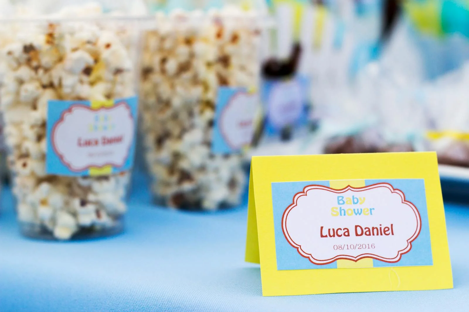 Popcorn treats with colorful labels at a baby shower celebration table.