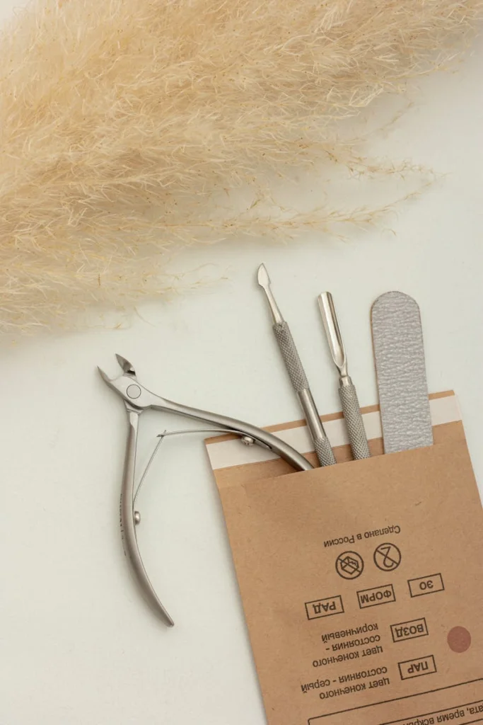 A minimalist flat lay of manicure tools in a brown packet with pampas grass.
