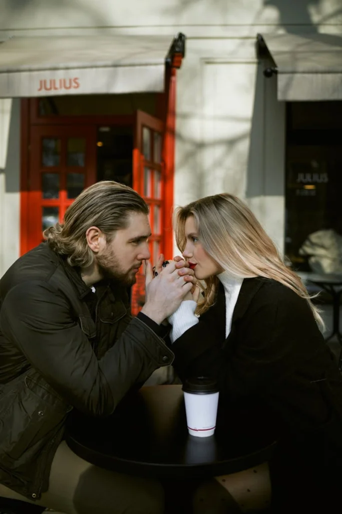 A couple shares an intimate moment over coffee outside a café. Perfect for love-themed projects.