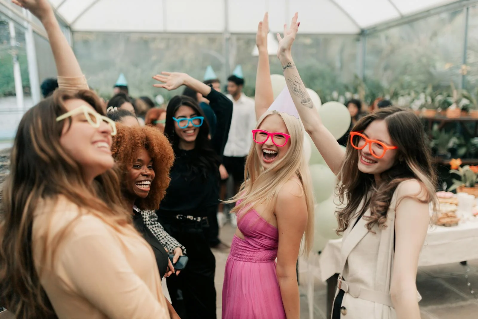 A lively indoor party with friends wearing colorful glasses, celebrating together joyfully.