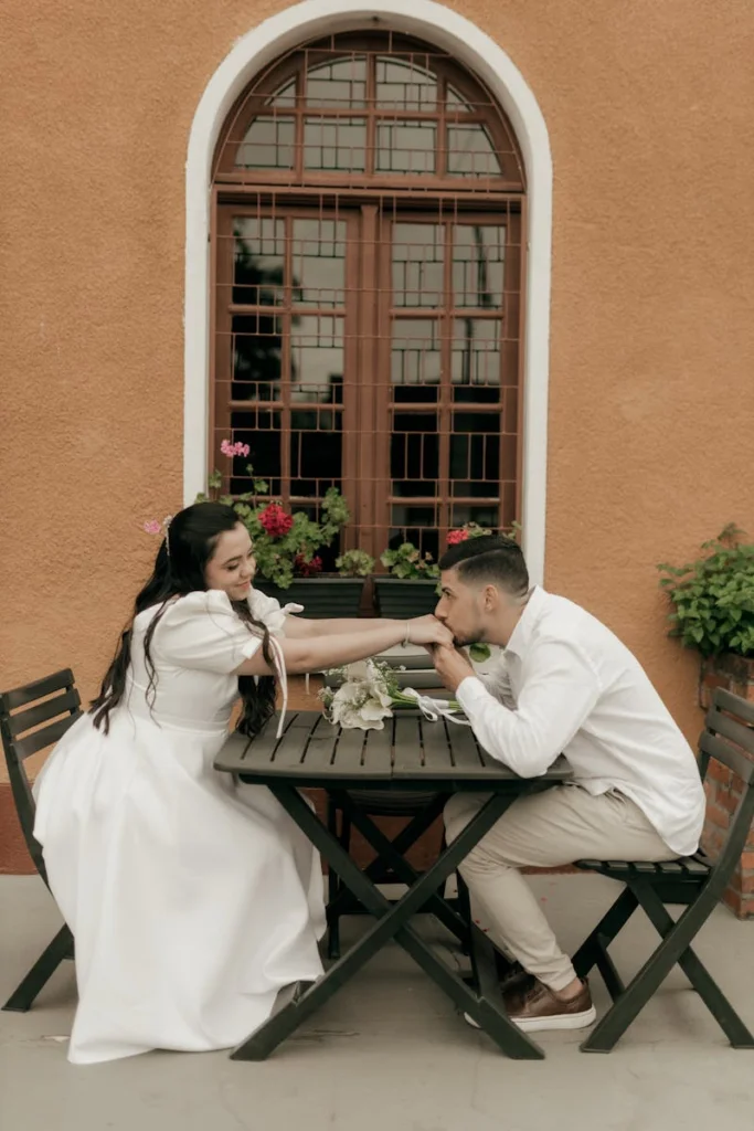 A loving couple enjoys a romantic meal at a quaint outdoor cafe on a sunny day.