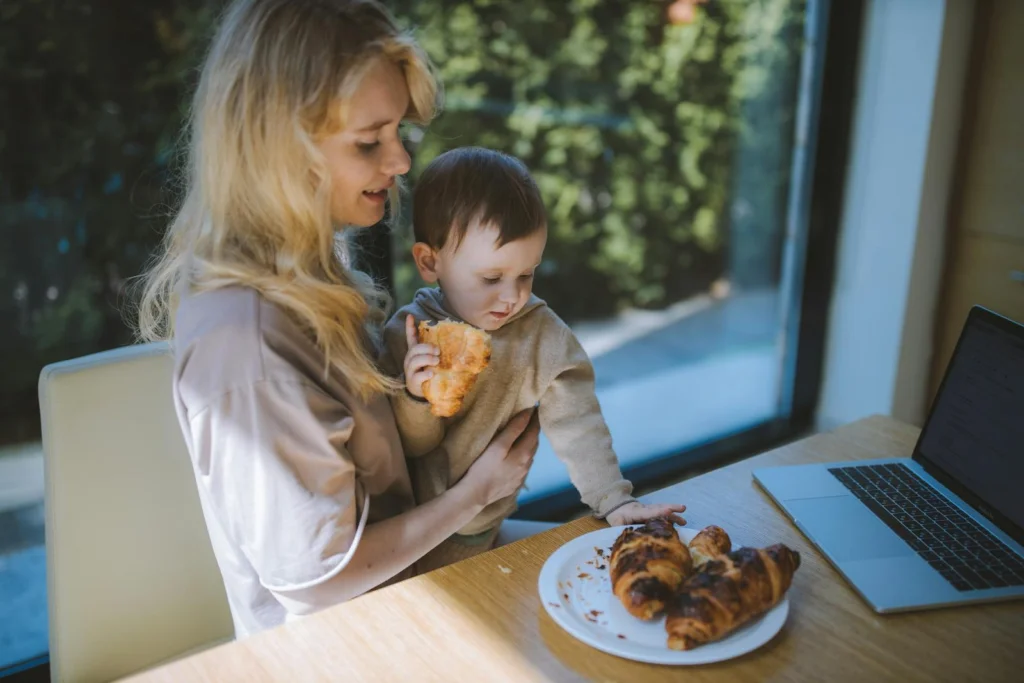 A mother and child share a joyful breakfast with croissants, embodying family togetherness at home.
