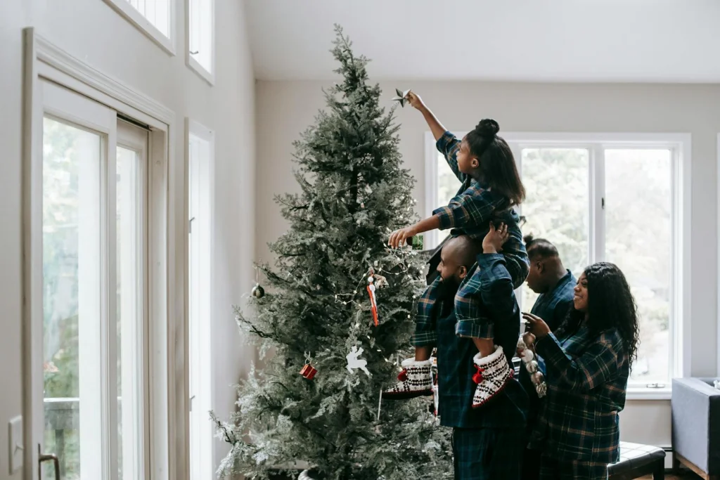 Family in matching pajamas decorating a Christmas tree at home.
