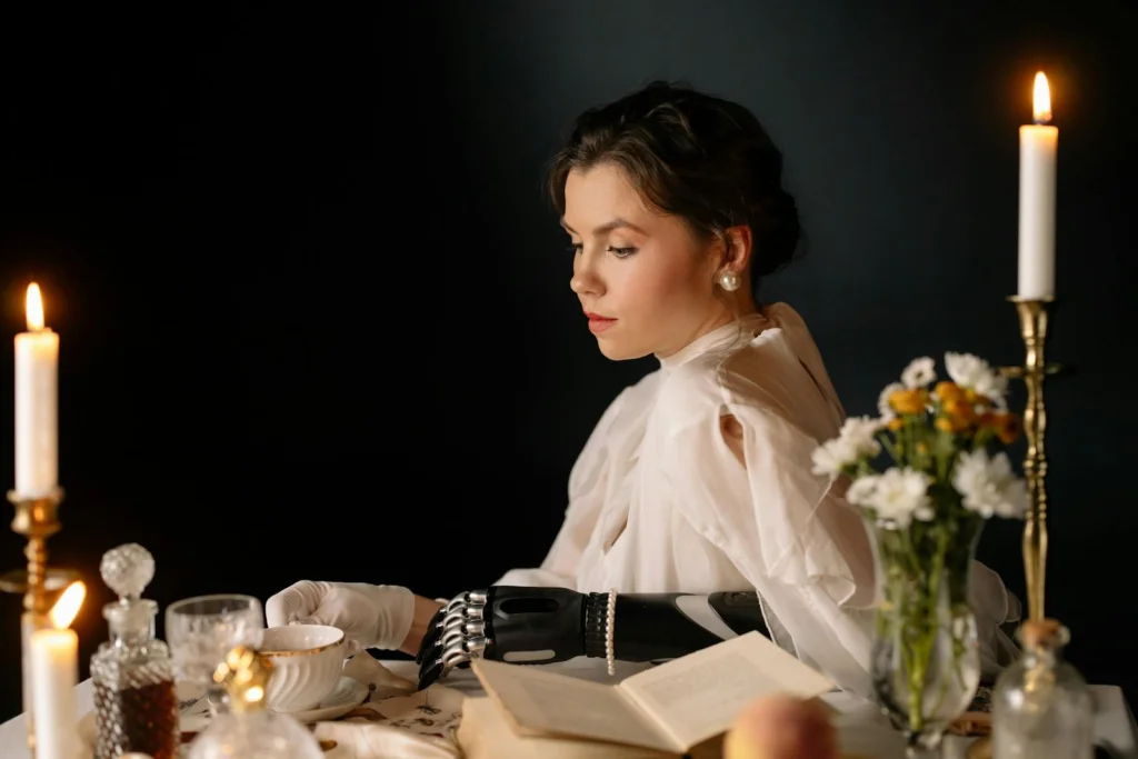 A woman with a prosthetic arm sits elegantly in a candlelit setting, exuding a vintage and romantic atmosphere.