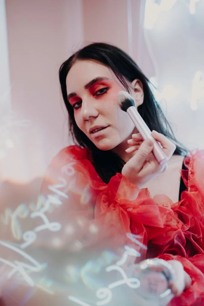 A stylish woman applying makeup, highlighted by soft focus text and red fashion elements.