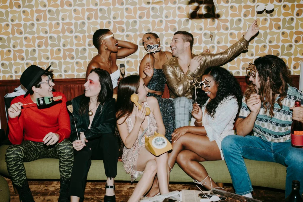 Group of friends enjoying a lively New Year's Eve party with laughter and festive decorations.