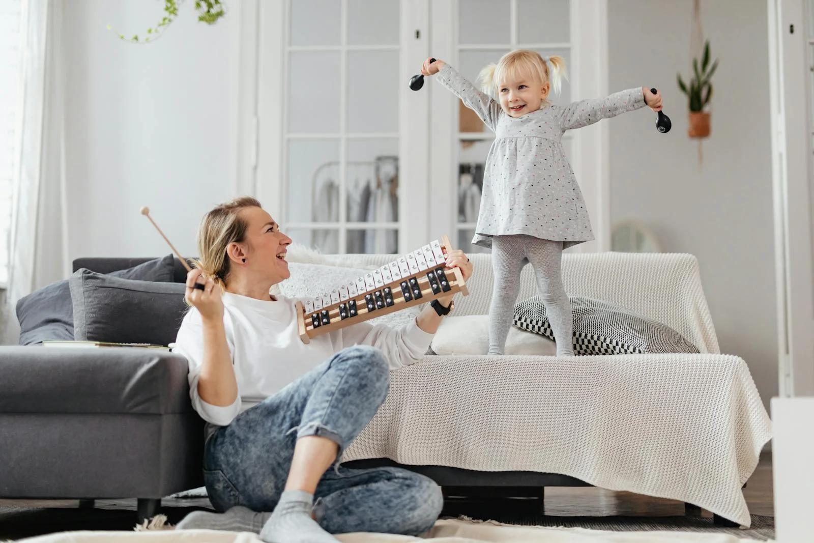 Mother and daughter enjoying music playtime at home with a xylophone. Happy and fun indoor activity.