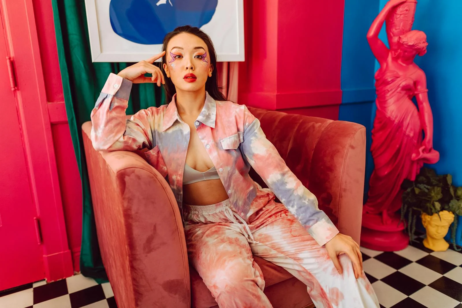 Artistic portrait of a stylish woman in vibrant attire in a colorful room setting.
