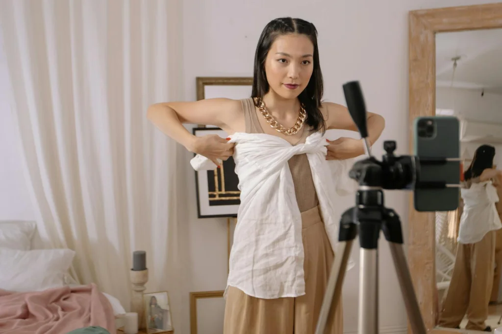 Fashion vlogger demonstrates styling tips while filming at home, enhancing personal fashion content.