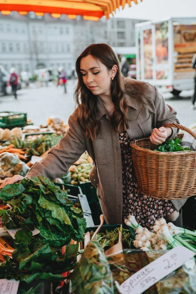 Caucasian woman shopping for fresh vegetables at an outdoor market in Erfurt, Germany.