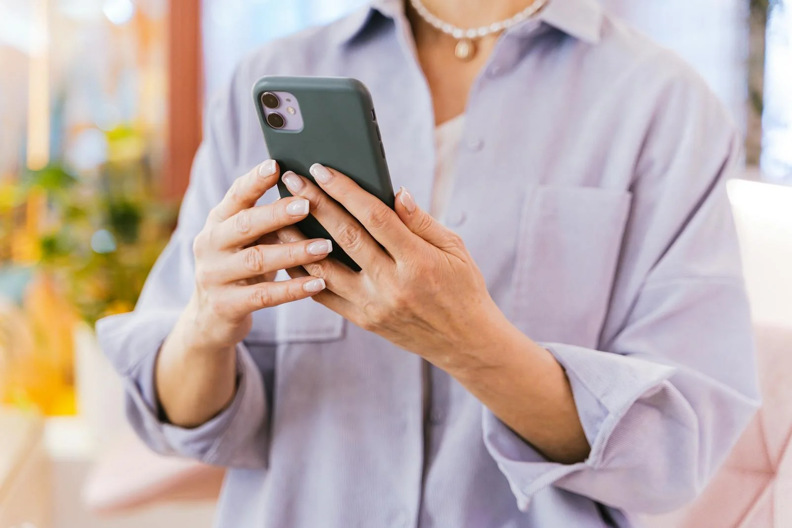 A close-up of an adult using a smartphone indoors, showcasing modern technology.