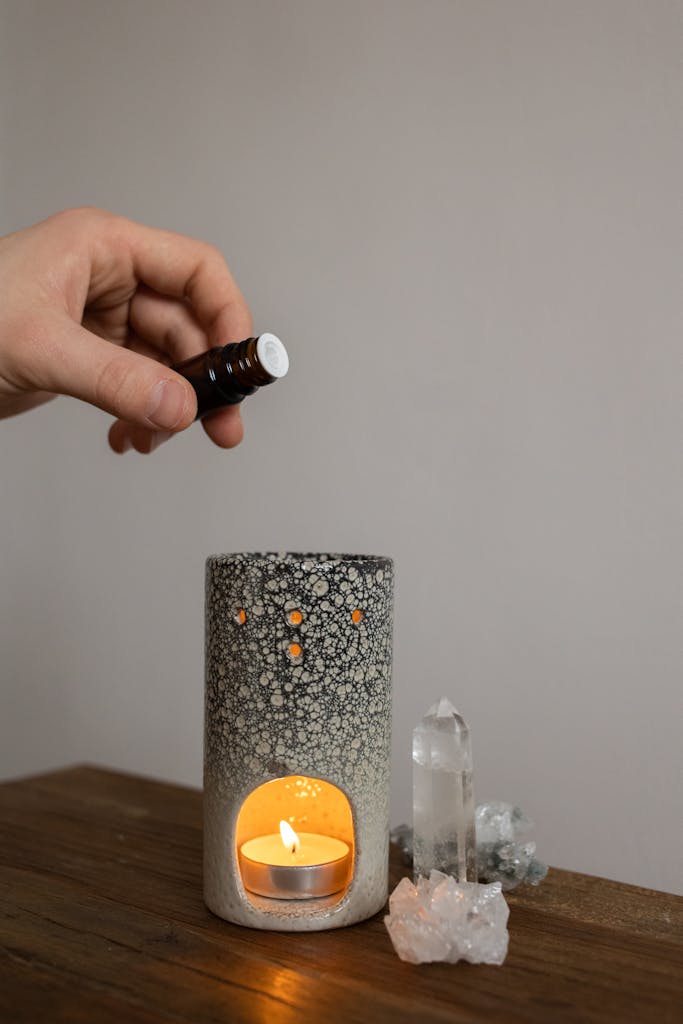 A cozy aromatherapy scene with candle holder, essential oil, and crystals creating a calm atmosphere.