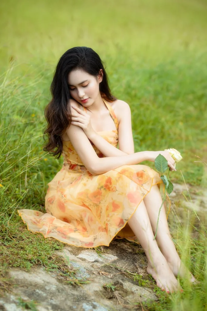 A woman in a yellow dress sitting on a rock