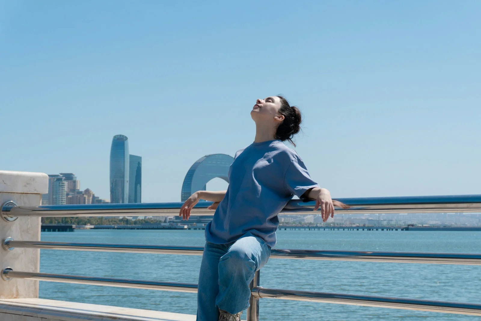 Woman enjoys the sun with water and city views.
