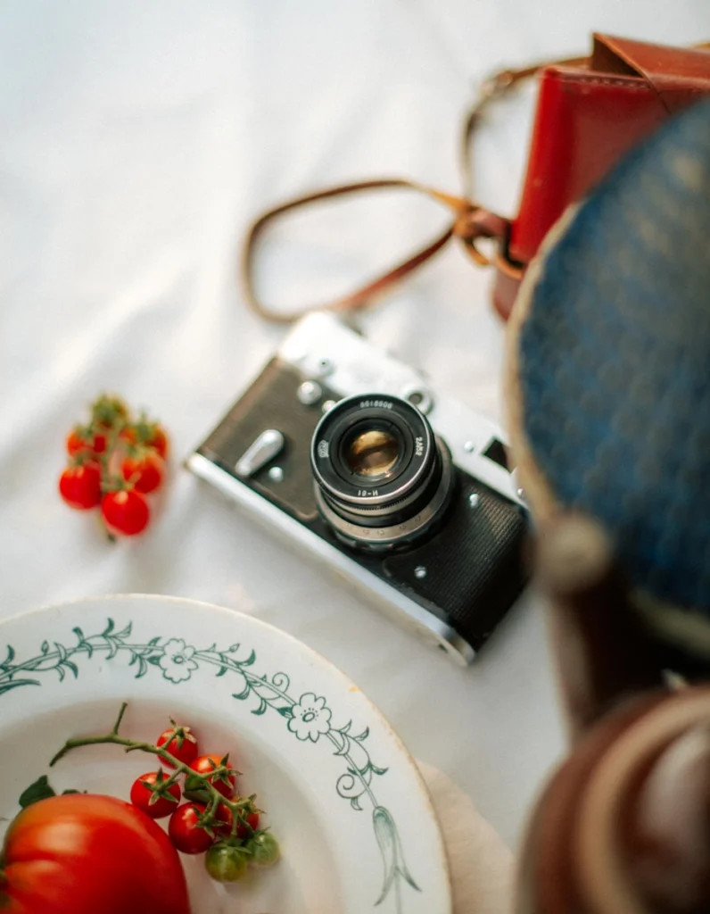 Vintage camera with tomatoes and plate on white cloth
