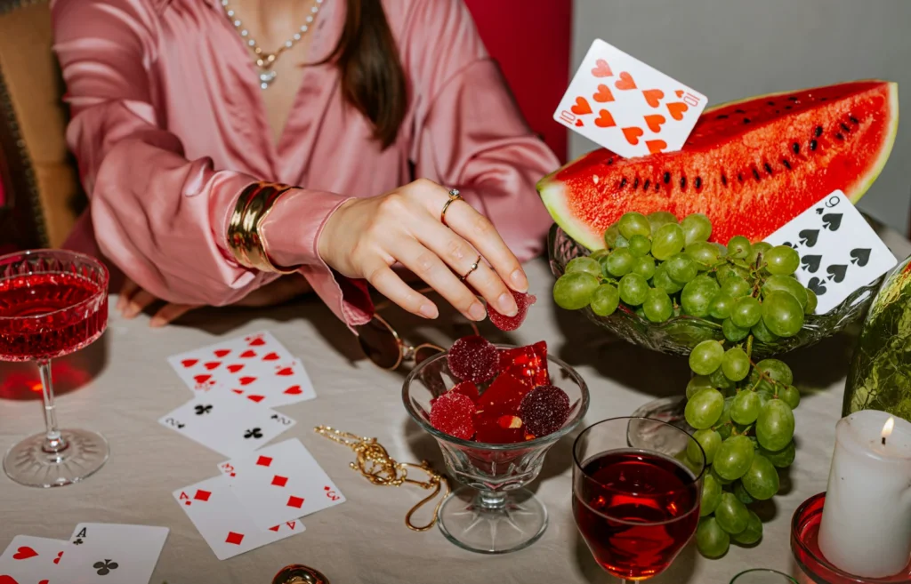 A woman sitting at a table with cards and a watermelon