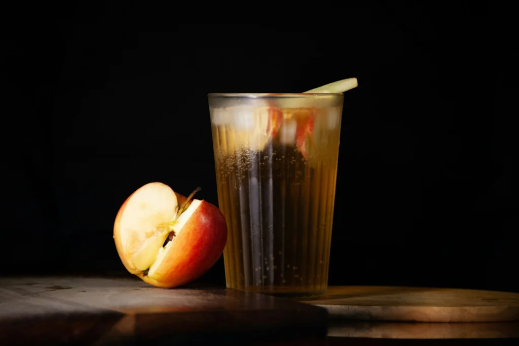 An apple and a glass of liquid on a table