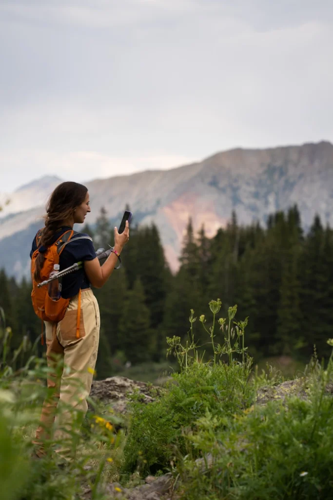 A woman standing in a field with a cell phone in her hand
