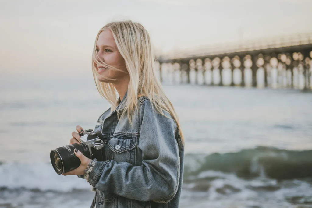 woman holding camera standing on seashore