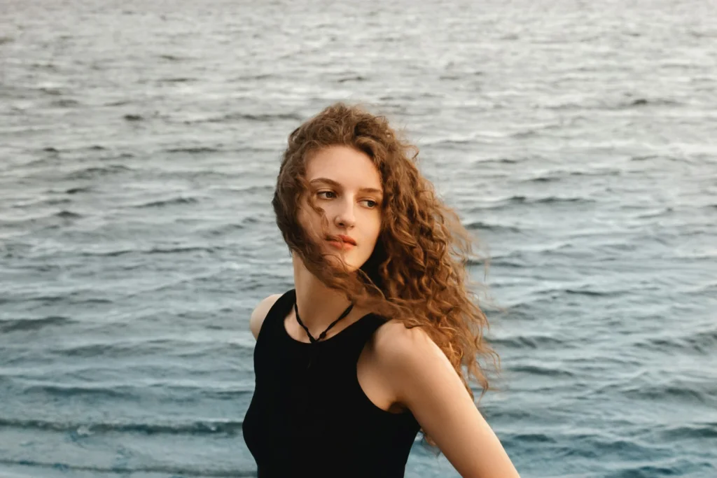 Woman poses by the wavy ocean waters.