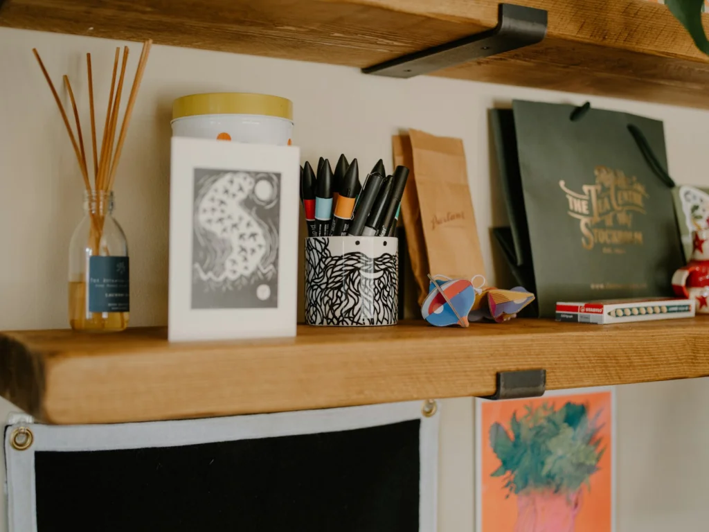 Wooden shelf with decorative items and art supplies.