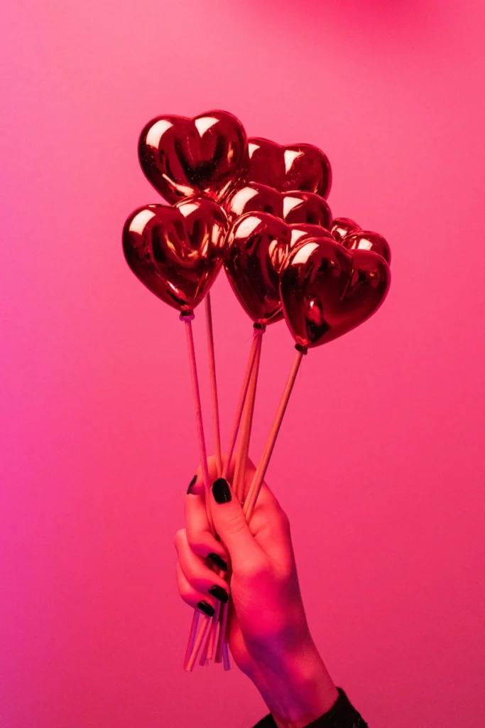 a person holding a bunch of heart shaped balloons