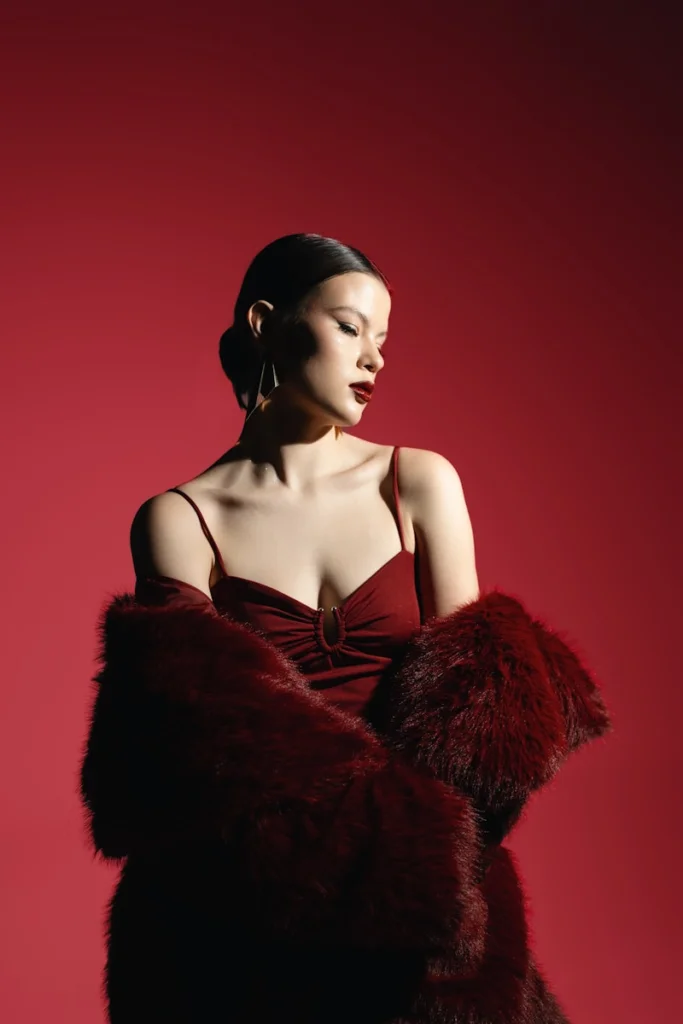 A woman poses in a glamorous, red outfit.