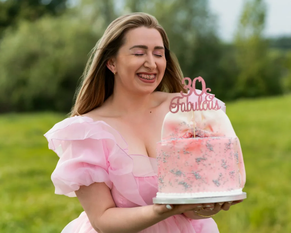 A woman in a pink dress holding a cake