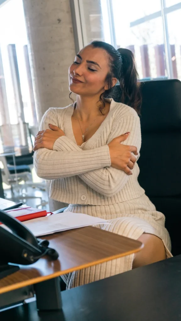 a woman sitting at a desk with her arms crossed
