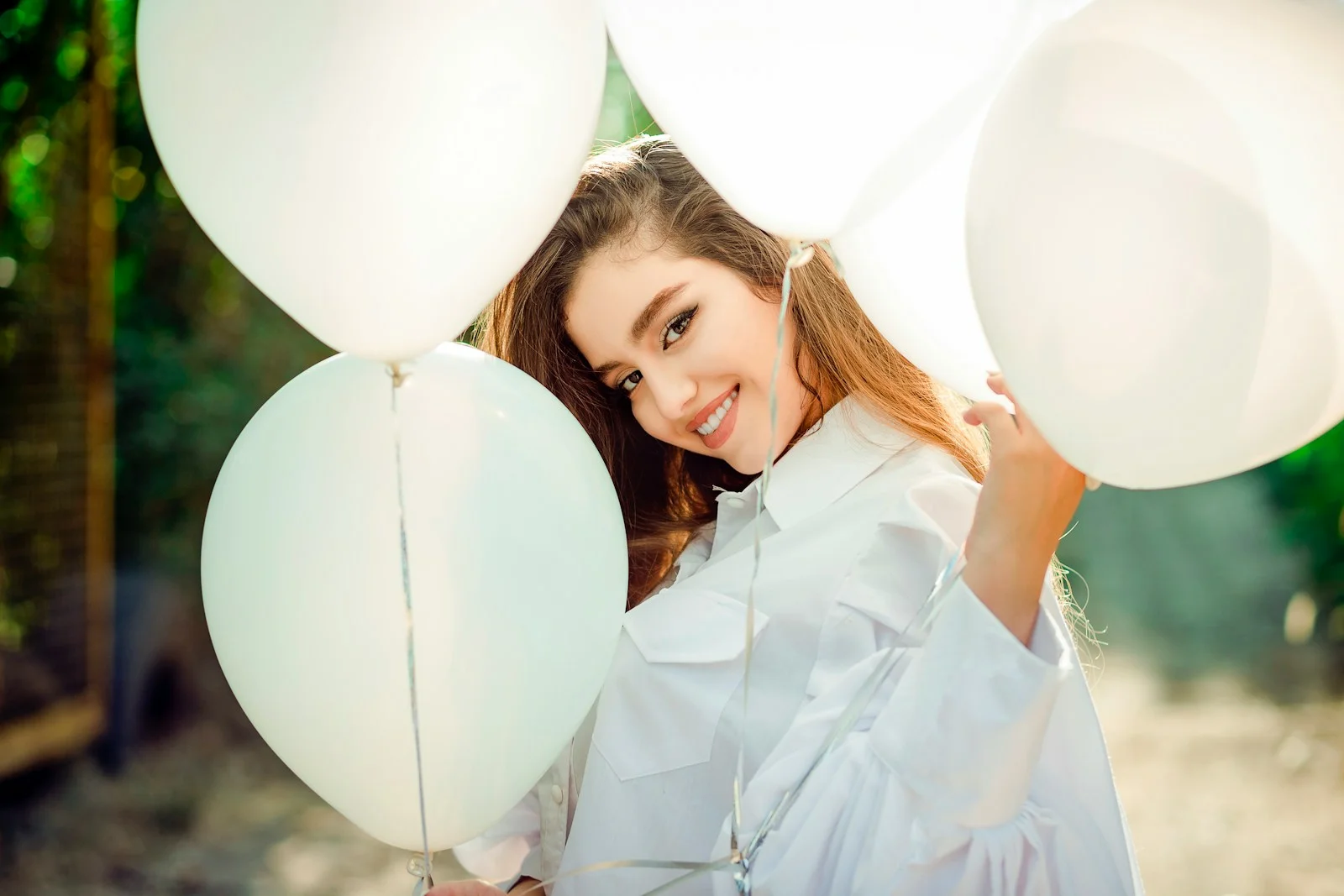 a woman holding a bunch of white balloons