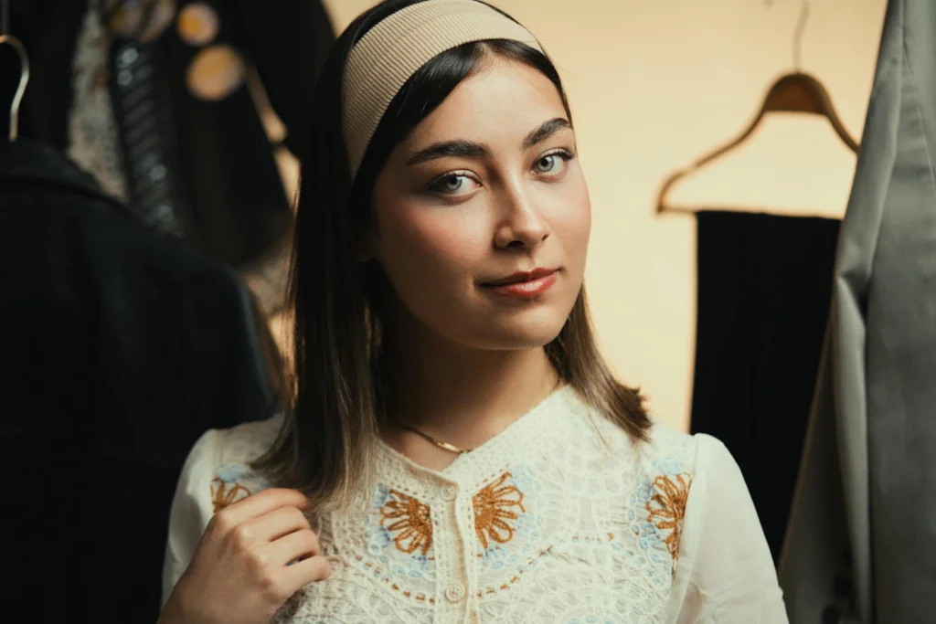 Stylish young woman wearing a vintage dress and headband, indoor setting.
