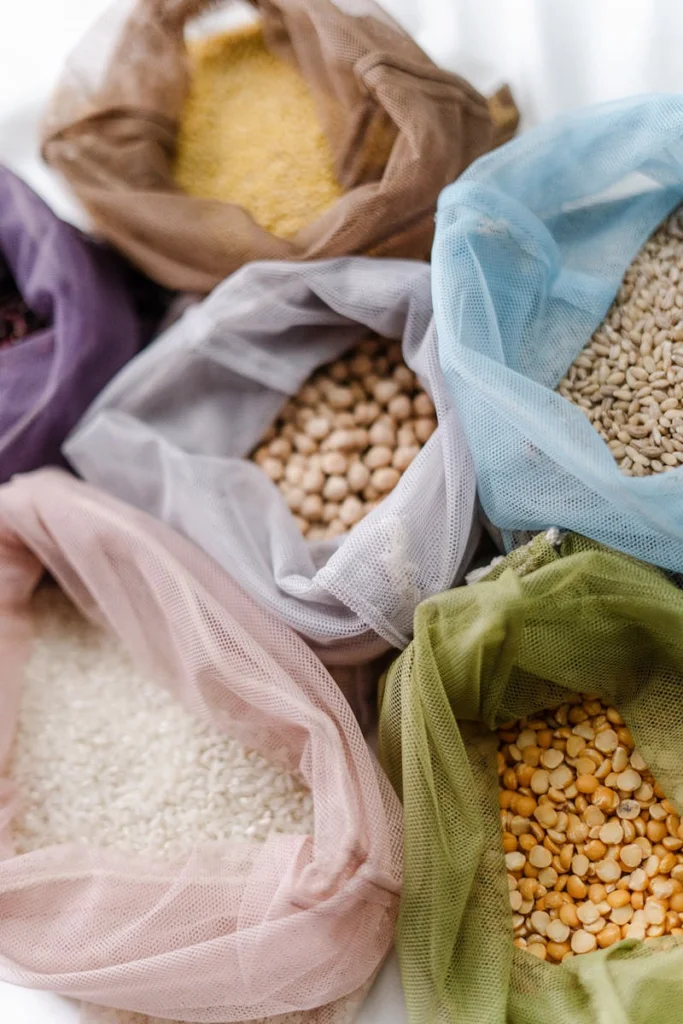 Colorful reusable bags filled with assorted grains and legumes, promoting eco-friendly food storage.