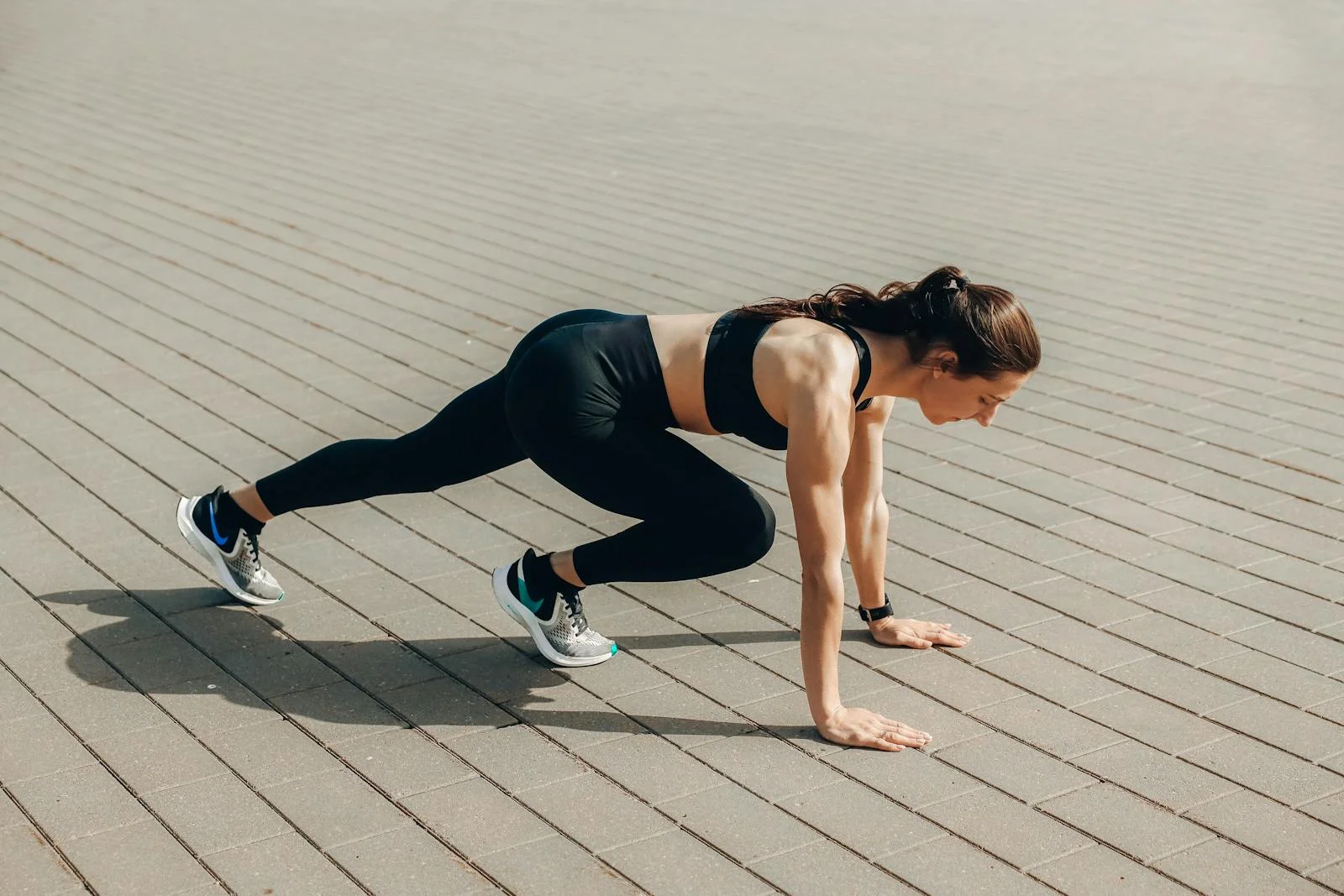 Woman in black sportswear doing an outdoor workout on a sunny day.