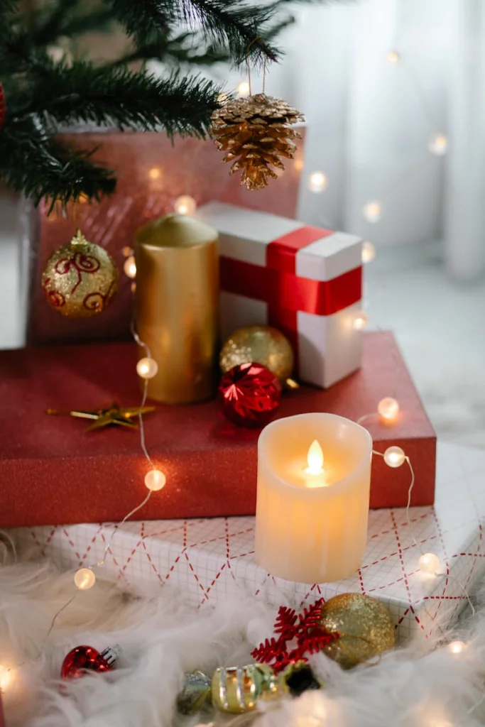 Festive Christmas scene with candles, gifts, and ornaments under a tree.