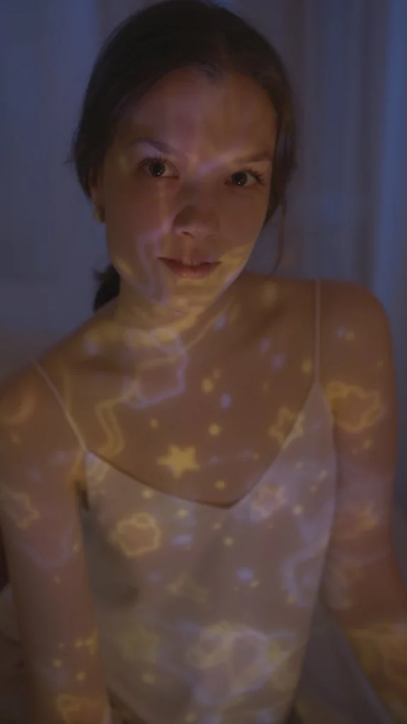 A dreamy portrait of a young woman with star projections in a bedroom setting, conveying imagination and tranquility.