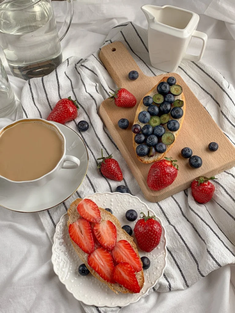 Top view of fruit-topped breakfast toasts with coffee on a striped cloth, styled elegantly.