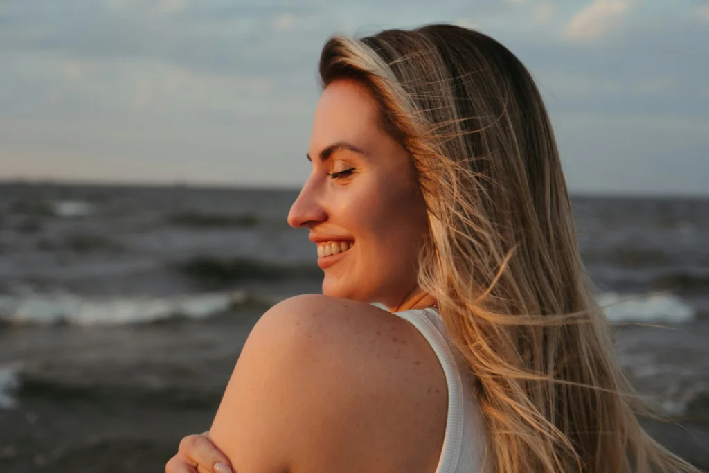 Smiling woman enjoys a beautiful sunset by the sea.