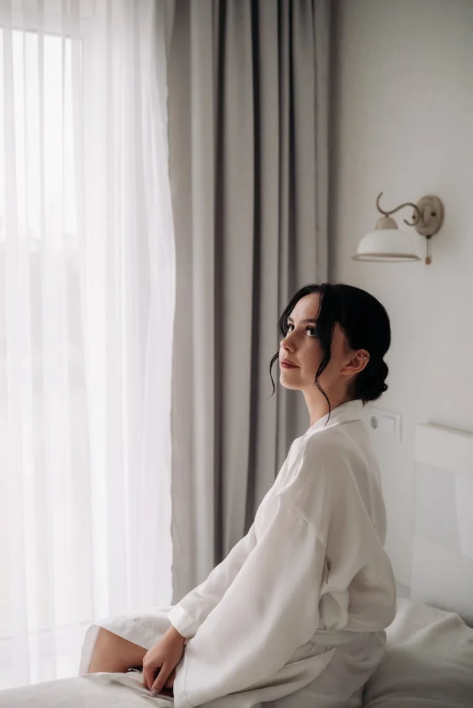 Woman in a bathrobe enjoying a calm morning in a bright hotel room.