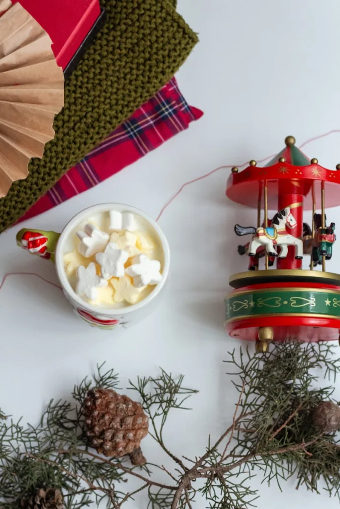 Cozy Christmas scene with hot chocolate, marshmallows, and carousel decor.