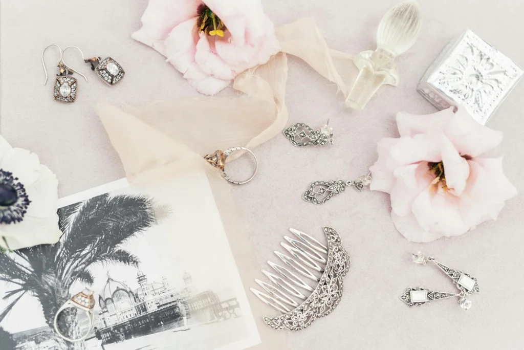 A delicate assortment of vintage jewelry and flowers in a flat lay composition.