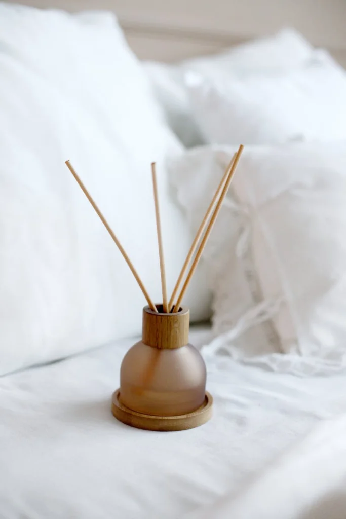 Elegant reed diffuser with wooden sticks on a bed of white linen for a serene home ambiance.