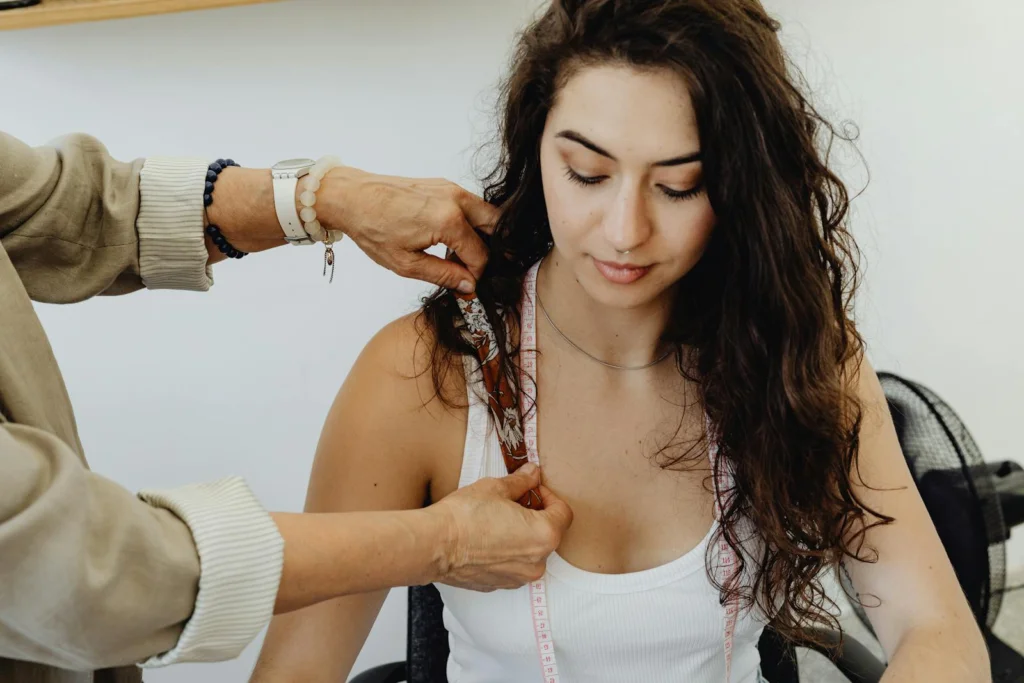 Young woman being measured with tape for tailoring indoors