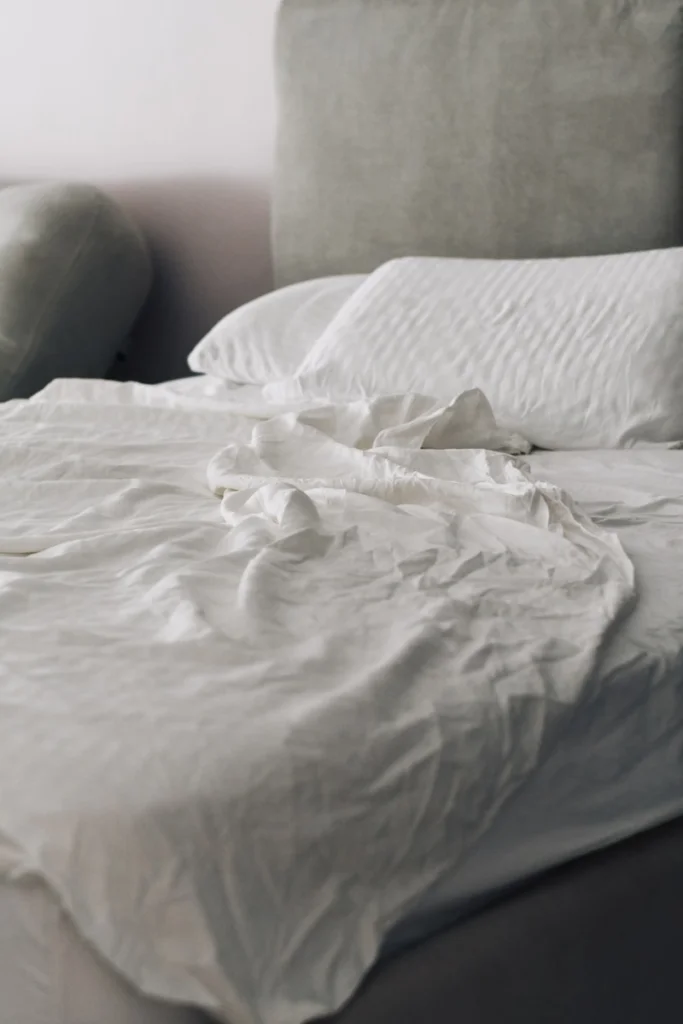 Neatly made bed with white linens and pillows.