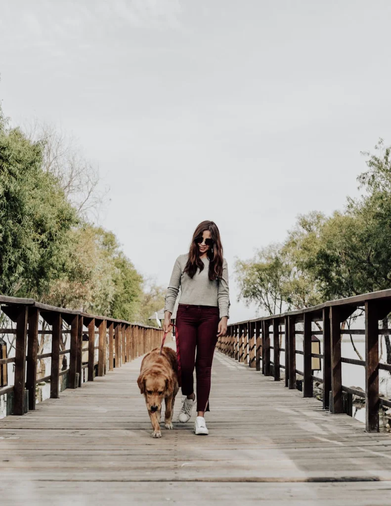 Woman with sunglasses walking dog on a wooden bridge in Jocotepec, Mexico.